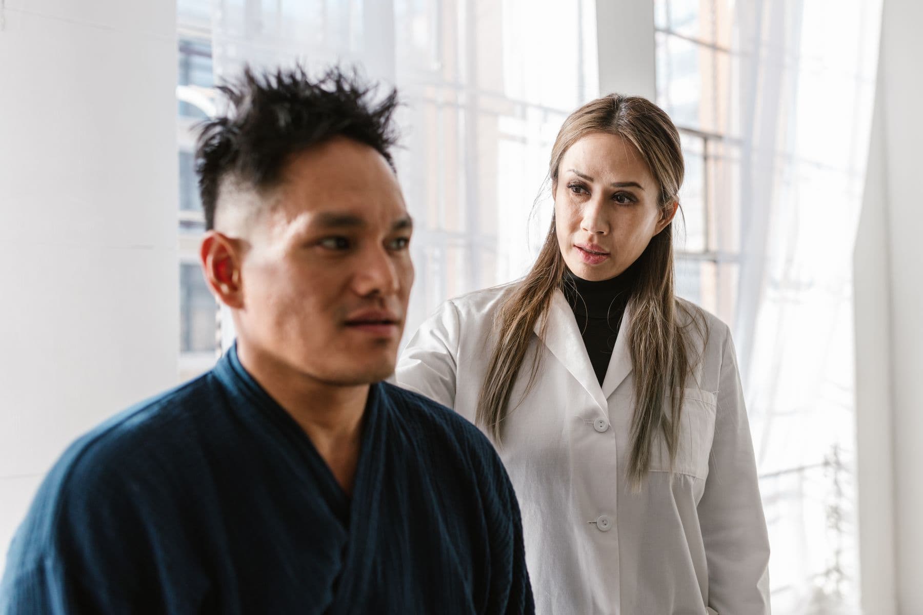 Khách hàng châu Á đang trao đổi với nhân sự y tế trong không gian nhiều ánh sáng.